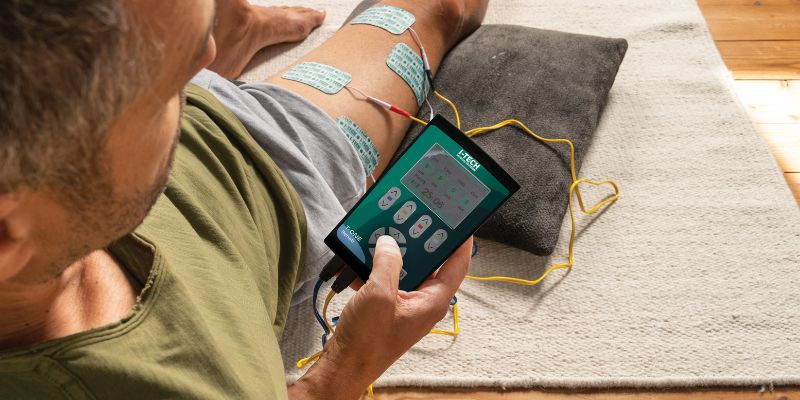 Hombre utilizando electroestimulador T-One en casa para tratar lesión en cuádriceps