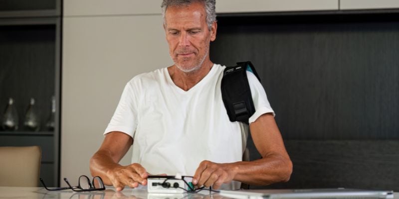 Hombre usando equipo de magnetoterapia en casa para tratar una lesión en hombro